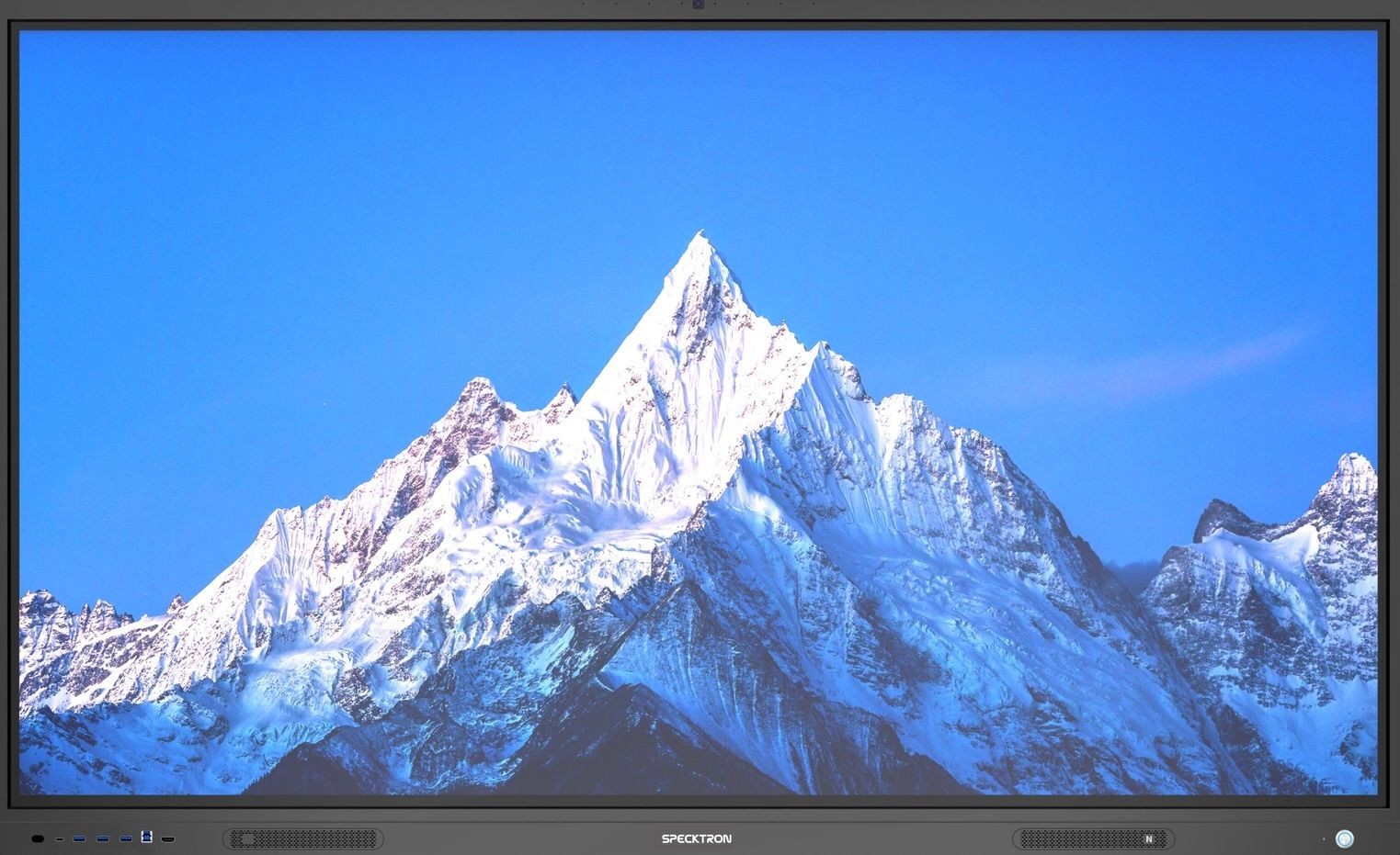 Sharp snow-covered mountain peak displayed on a screen with a clear blue sky background.